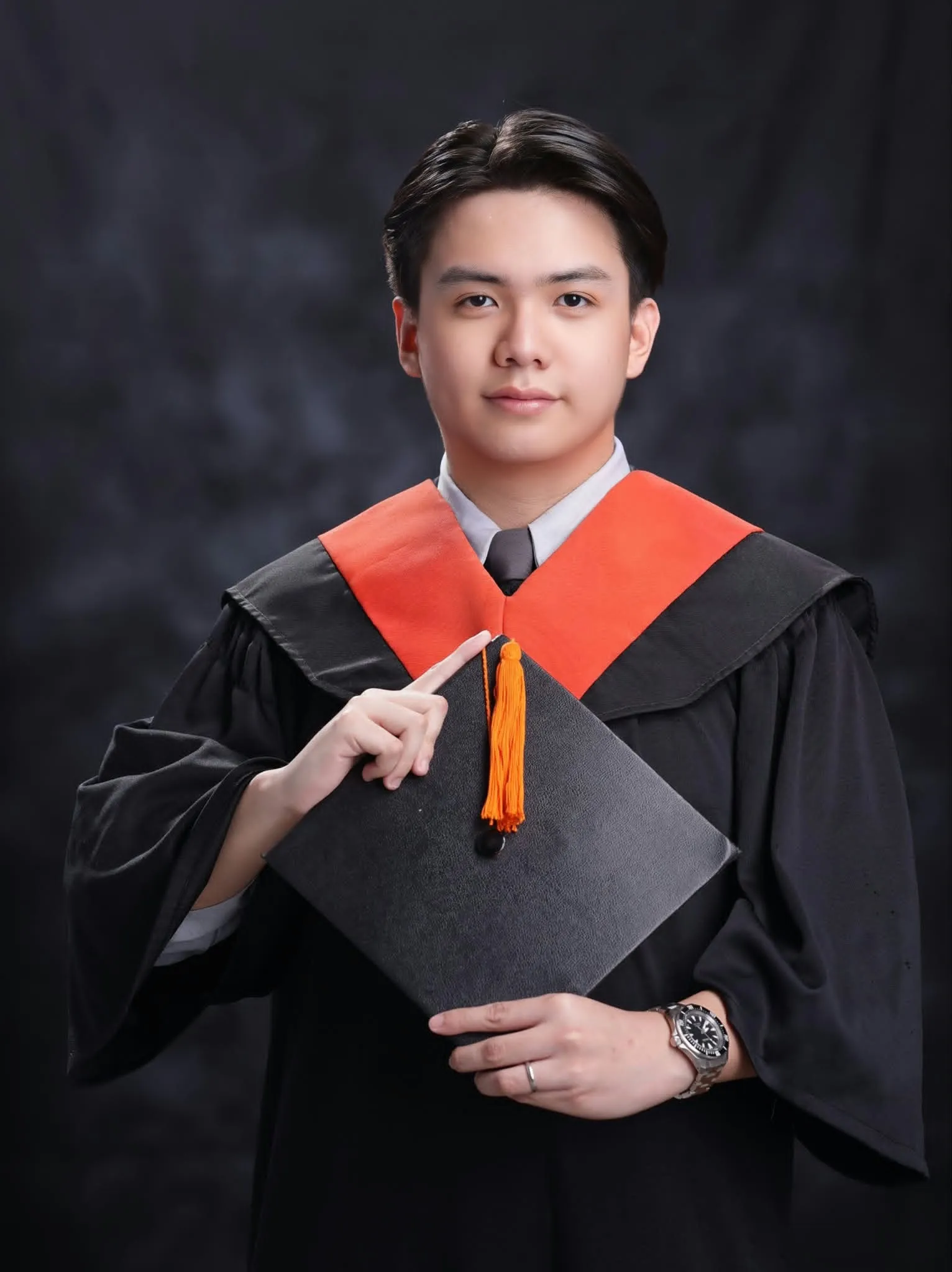 Carl Balaria in his graduation toga, holding his cap
